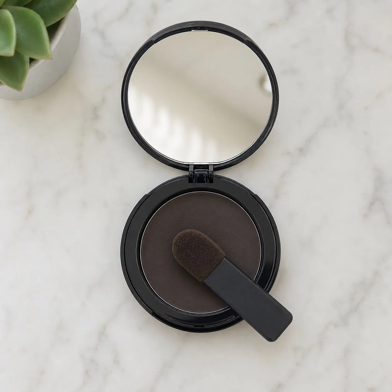 Open Thicken It compact photographed from above with its slim foam applicator resting on the pressed cotton fiber powder